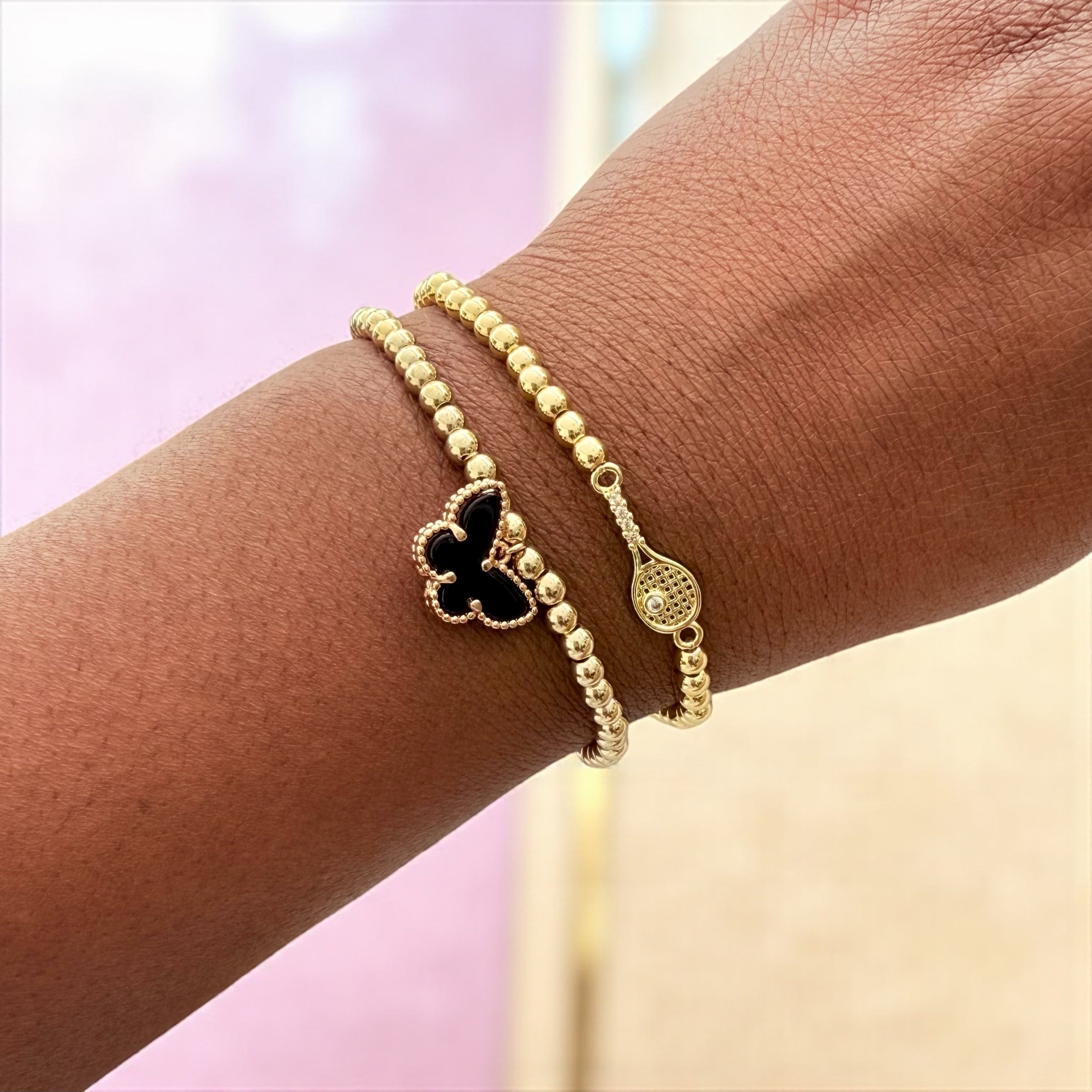 Gold beaded bracelet with a black clover charm.