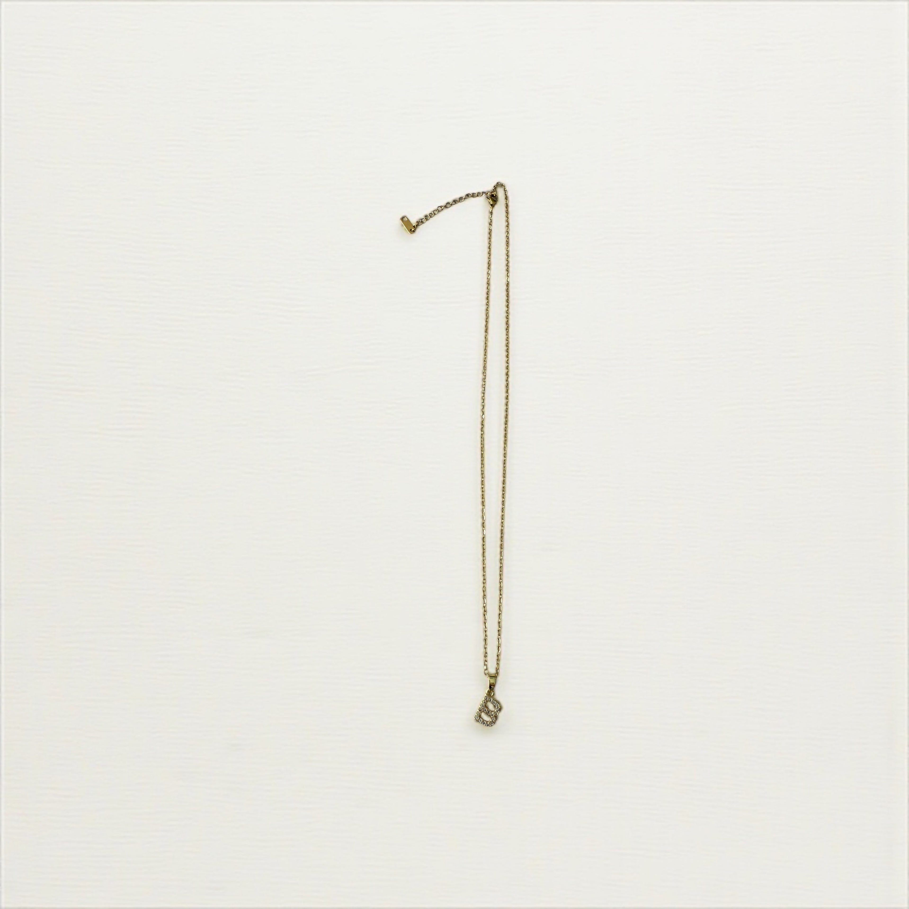 . Gold toned necklace with a crystal-encrusted initial "B” pendant.